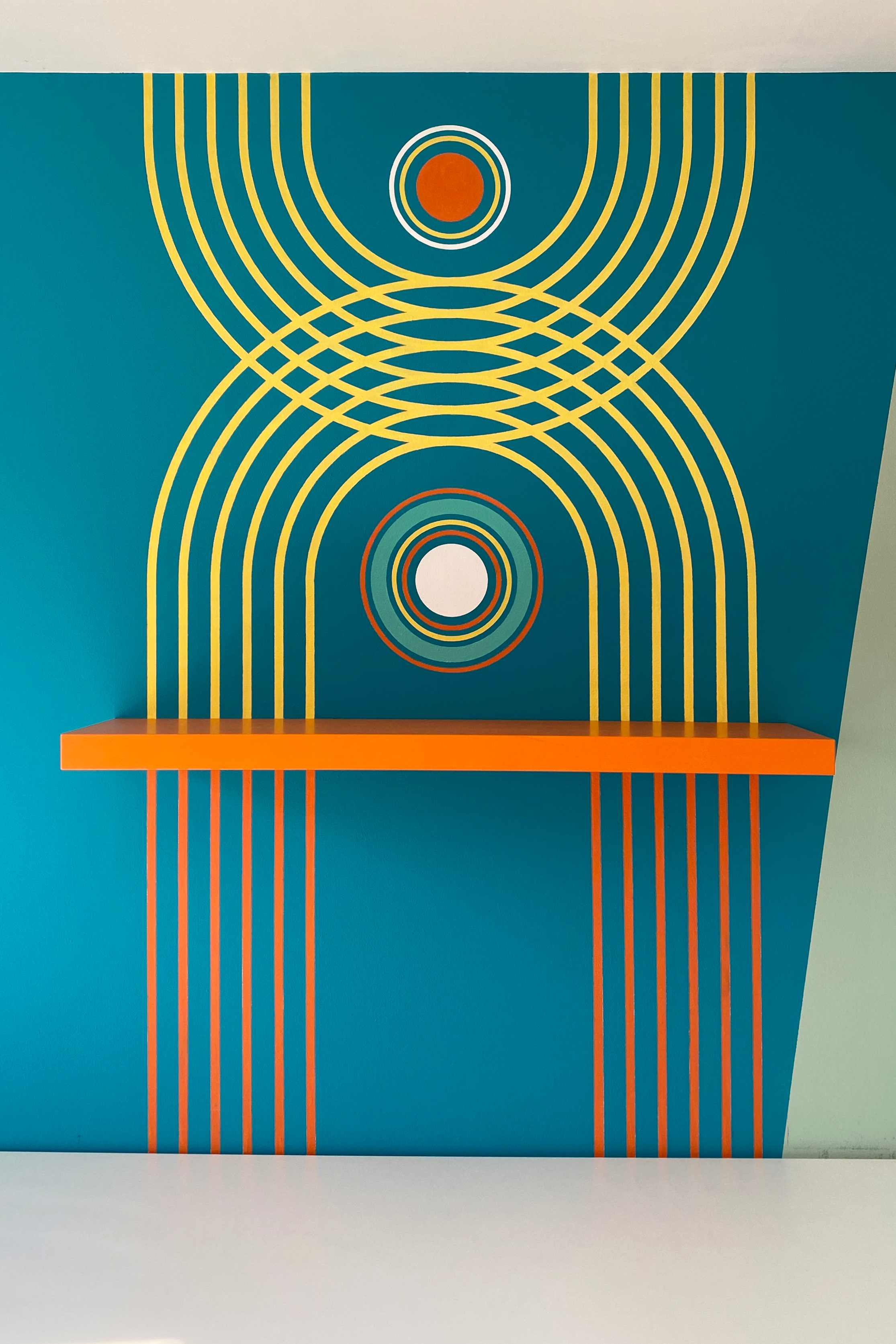 wandmalerei kreise und linien in kräftigen farben mit orangem regal